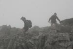 A team descend rocky ground in the mist